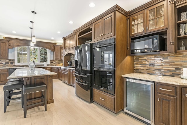 kitchen with light stone countertops, decorative light fixtures, wine cooler, and black appliances