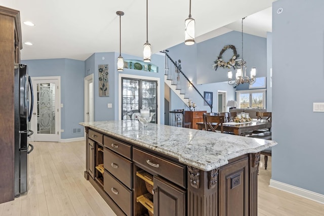 kitchen with light stone counters, decorative light fixtures, dark brown cabinets, and a center island