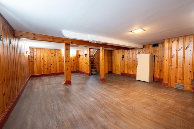 basement with dark hardwood / wood-style flooring, wood walls, and white fridge