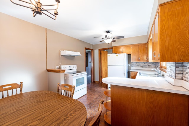 kitchen with sink, kitchen peninsula, white appliances, ceiling fan with notable chandelier, and backsplash