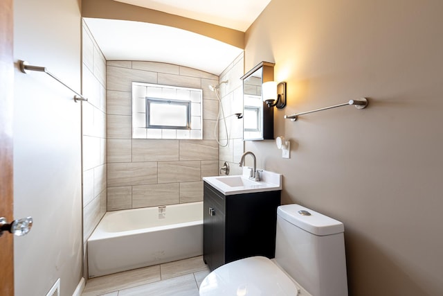 full bathroom with vaulted ceiling, tiled shower / bath, tile patterned flooring, vanity, and toilet