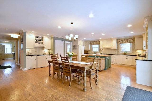 dining area featuring light wood-style flooring, baseboards, crown molding, and recessed lighting