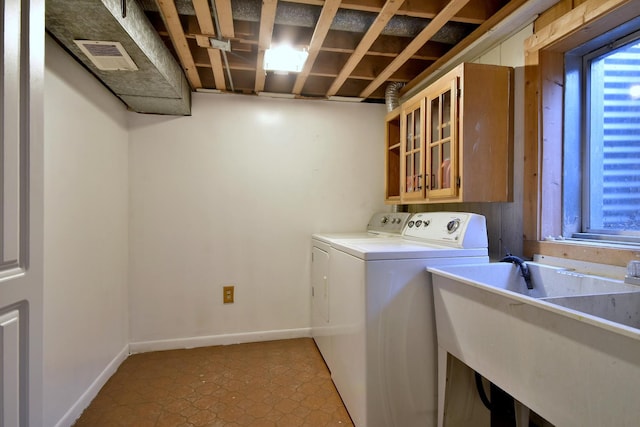 clothes washing area with visible vents, a sink, baseboards, and separate washer and dryer