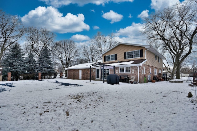 snow covered house featuring brick siding