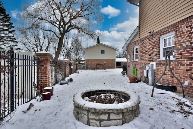 yard covered in snow with an outdoor fire pit and fence