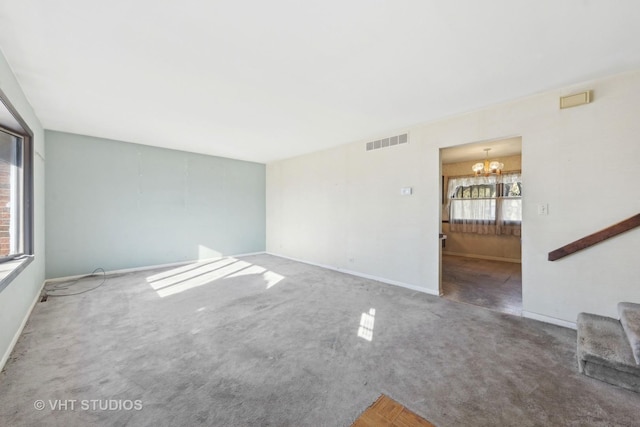 unfurnished living room featuring an inviting chandelier and carpet