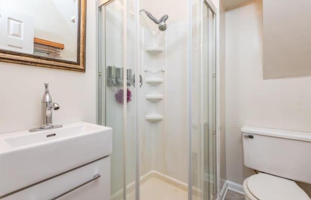 bathroom with sink, an enclosed shower, and toilet