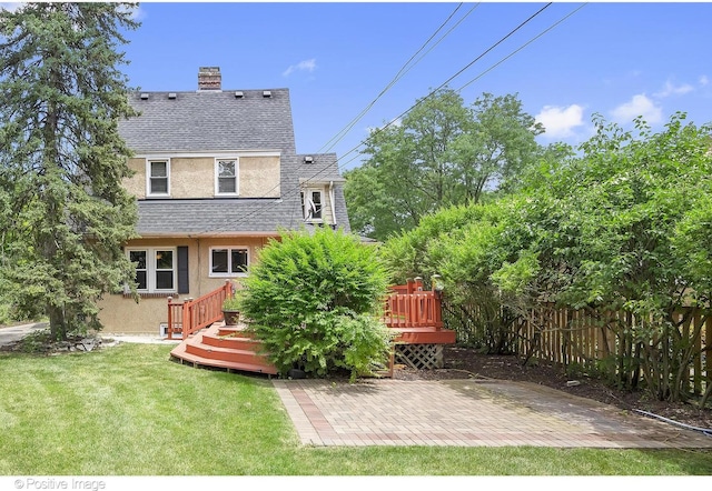 rear view of house featuring a wooden deck, a yard, and a patio