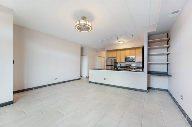 kitchen featuring stainless steel appliances, rail lighting, light brown cabinetry, and sink