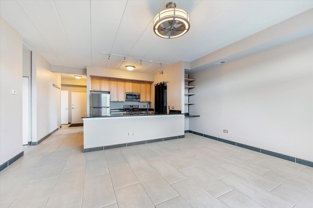 kitchen featuring appliances with stainless steel finishes, rail lighting, kitchen peninsula, and light brown cabinets