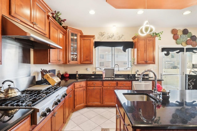 kitchen with stainless steel gas stovetop, light tile patterned flooring, sink, and dark stone counters