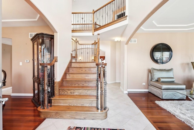 stairway with hardwood / wood-style flooring and a towering ceiling