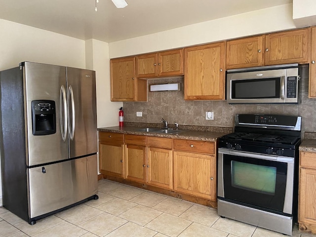 kitchen with sink, decorative backsplash, light tile patterned floors, and appliances with stainless steel finishes