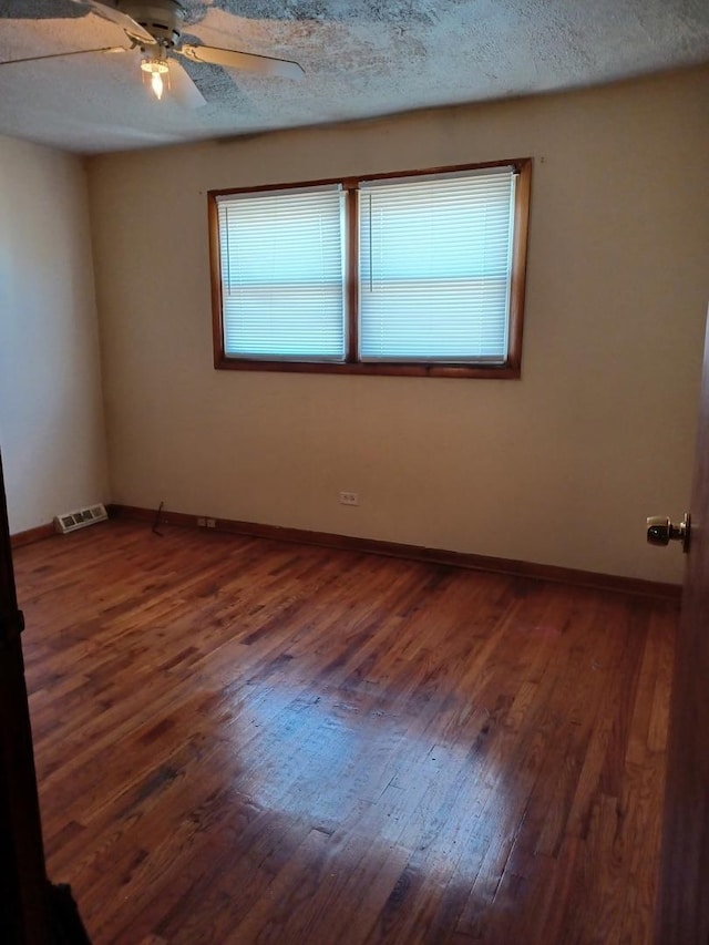 empty room featuring ceiling fan, dark hardwood / wood-style flooring, and a textured ceiling