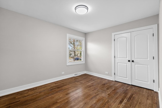 unfurnished bedroom featuring dark hardwood / wood-style flooring and a closet