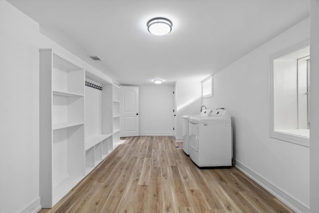 laundry area featuring independent washer and dryer and light hardwood / wood-style floors