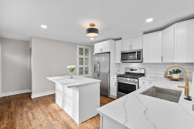 kitchen featuring light stone counters, stainless steel appliances, a center island, and white cabinets