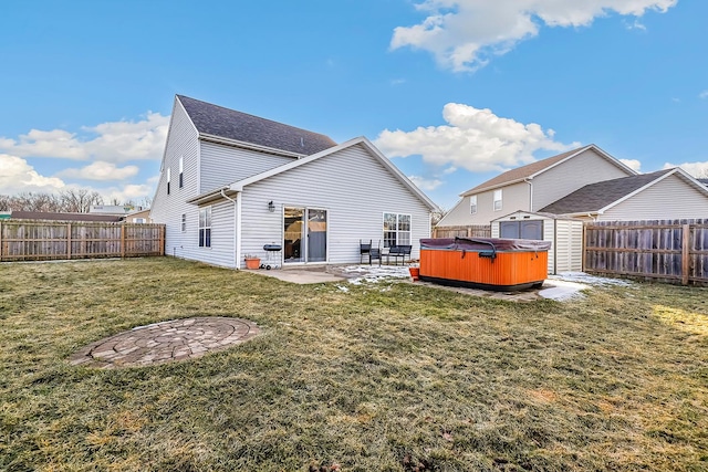 back of house with a hot tub, a patio, a storage shed, and a lawn