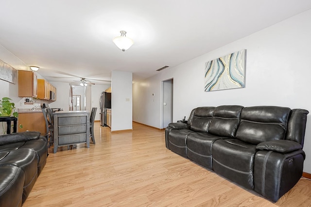 living room with ceiling fan and light hardwood / wood-style flooring