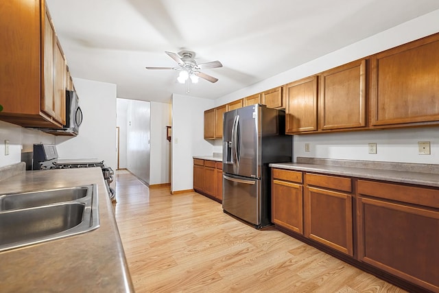 kitchen featuring ceiling fan, stainless steel appliances, sink, and light wood-type flooring