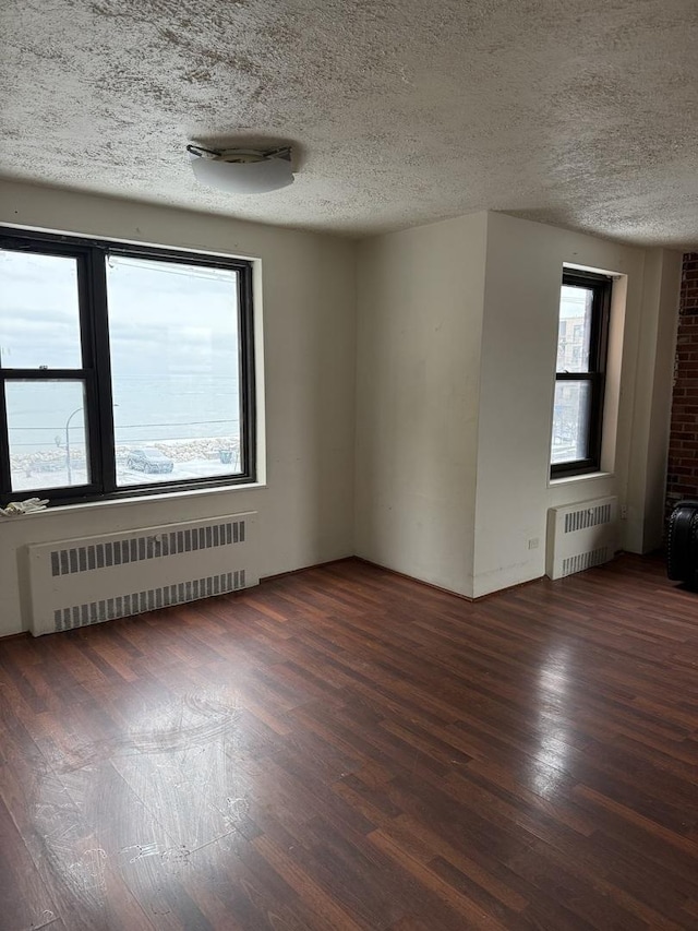 empty room featuring dark hardwood / wood-style floors, radiator, and a textured ceiling