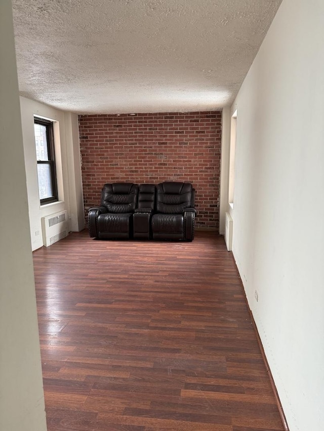 unfurnished living room with dark hardwood / wood-style floors, radiator, and a textured ceiling