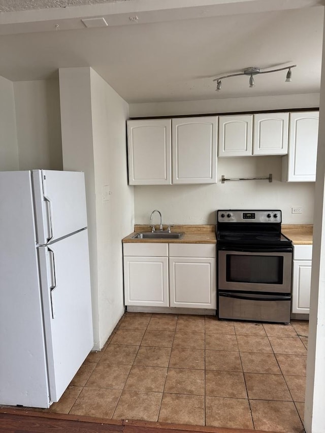 kitchen with sink, white cabinets, stainless steel range with electric stovetop, white fridge, and light tile patterned floors