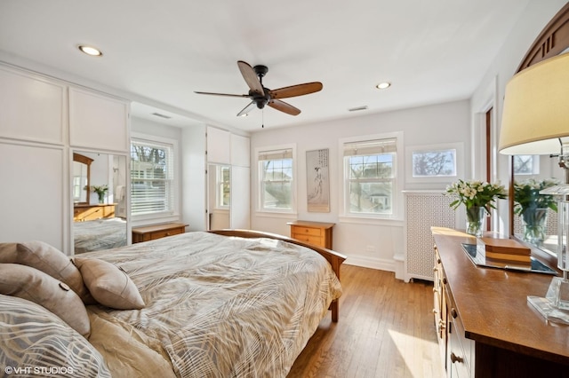 bedroom featuring hardwood / wood-style flooring, ceiling fan, and multiple windows