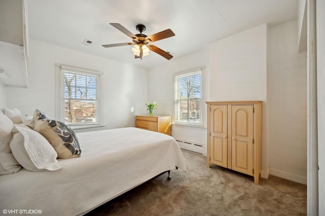 bedroom with baseboard heating, ceiling fan, multiple windows, and light carpet