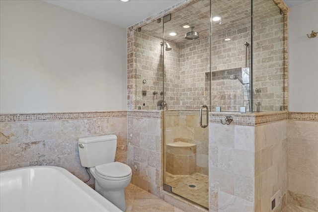 bathroom with toilet, tile walls, and plus walk in shower