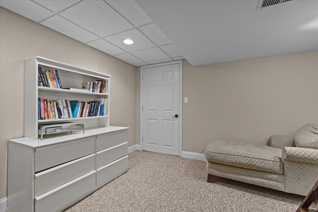 living area featuring carpet flooring and a drop ceiling