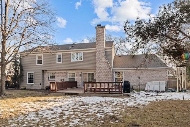 snow covered rear of property featuring a yard and a deck