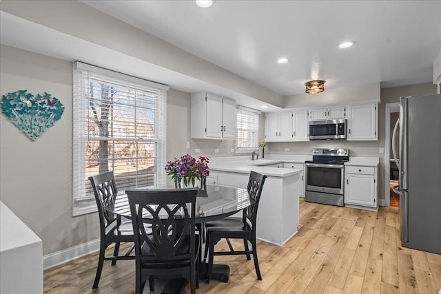 kitchen with white cabinetry, appliances with stainless steel finishes, sink, and light wood-type flooring