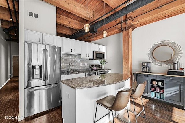 kitchen featuring white cabinetry, sink, dark stone counters, hanging light fixtures, and stainless steel appliances