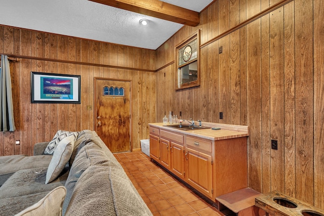 interior space with vanity, tile patterned flooring, beamed ceiling, and wood walls