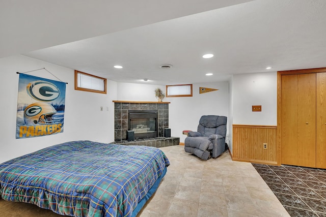 bedroom featuring wooden walls and a tiled fireplace