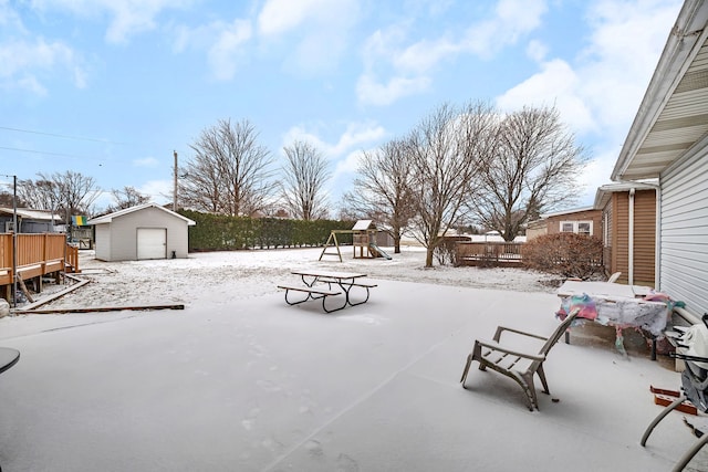 snow covered patio featuring a storage shed and a playground