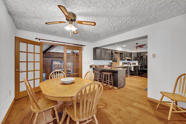 dining area with sink, a textured ceiling, ceiling fan, and light hardwood / wood-style flooring