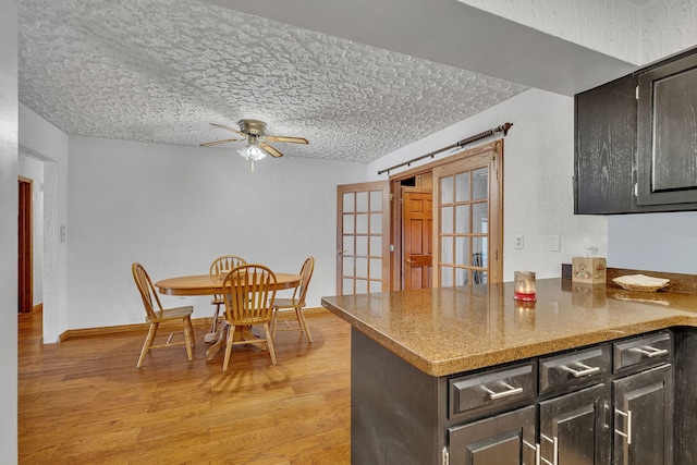 kitchen with light stone counters, ceiling fan, light hardwood / wood-style floors, and a textured ceiling