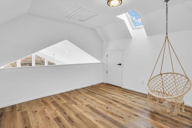 additional living space with hardwood / wood-style flooring and vaulted ceiling with skylight