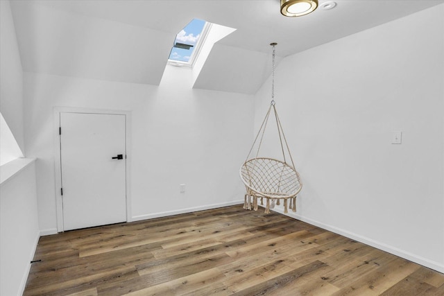 additional living space with hardwood / wood-style flooring and vaulted ceiling with skylight