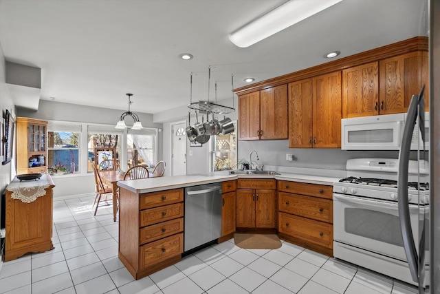 kitchen with sink, decorative light fixtures, light tile patterned floors, kitchen peninsula, and white appliances