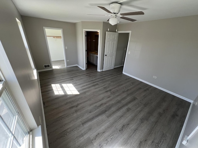 unfurnished bedroom featuring connected bathroom, a spacious closet, dark hardwood / wood-style flooring, a closet, and ceiling fan