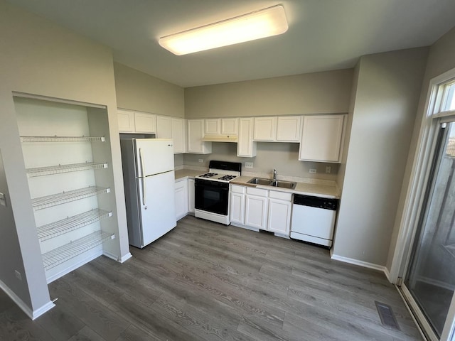 kitchen with lofted ceiling, sink, white cabinets, hardwood / wood-style flooring, and white appliances