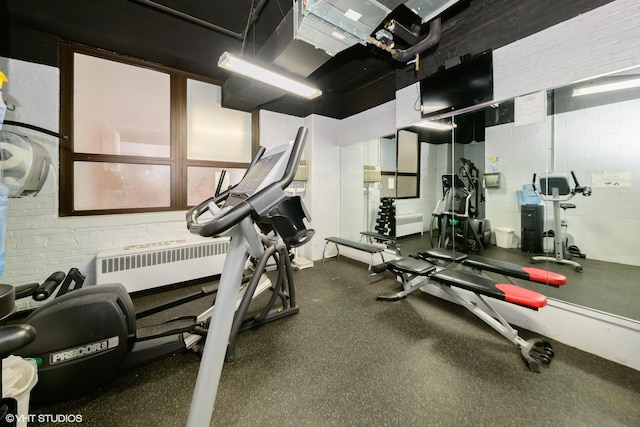 workout area featuring radiator and brick wall