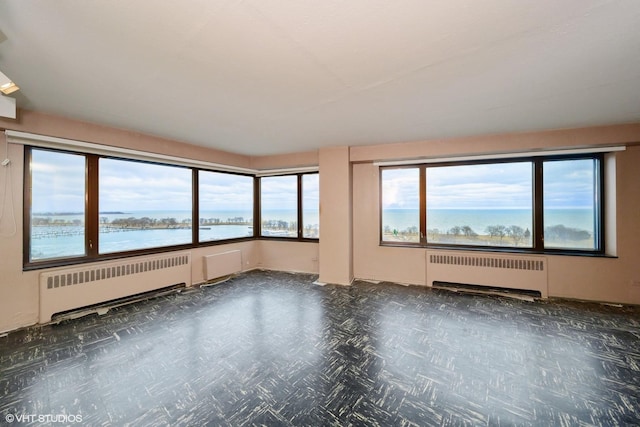 empty room featuring a water view and radiator heating unit