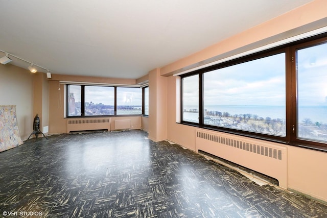 unfurnished room featuring radiator heating unit and rail lighting