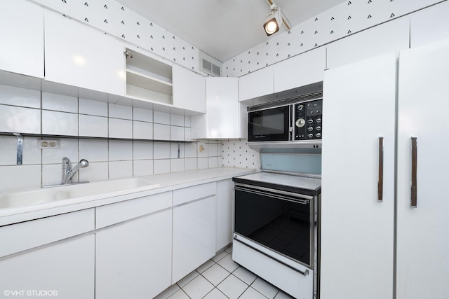 kitchen featuring range with electric stovetop, tasteful backsplash, white cabinetry, sink, and white refrigerator