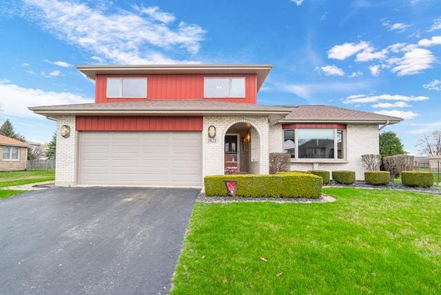 view of front of house featuring a front lawn, an attached garage, brick siding, and aphalt driveway