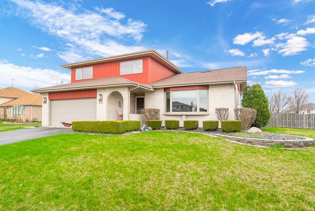 traditional home with a garage, brick siding, fence, driveway, and a front yard